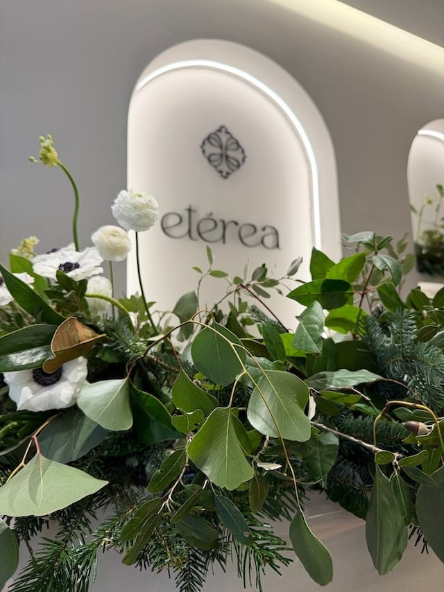Primer plano del logotipo de Clínica Etérea en Valencia sobre un arco iluminado y rodeado de flores naturales de A flor de Piel.