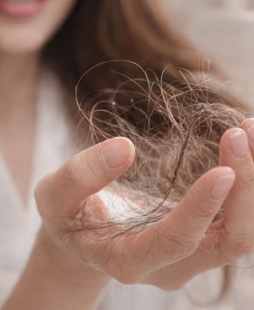 Mujer observando caída del cabello en sus manos en Clínica Etérea Valencia, imagen representativa de pérdida capilar femenina.